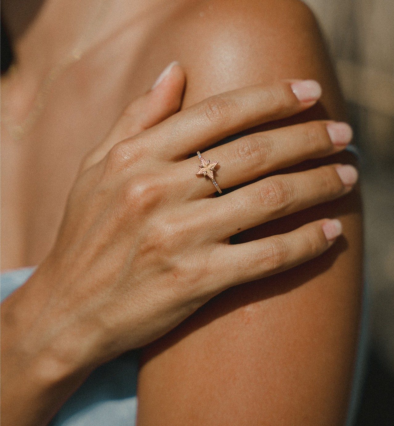 Hand mit Sternring auf gebräunter Schulter